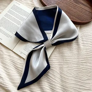 Detail eines eleganten blau-silbernen Satinschals mit einer funkelnden Strassschnalle