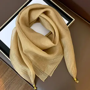 Detailansicht eines goldenen Satin-Halstuchs mit dezentem Schimmer und goldener Quaste