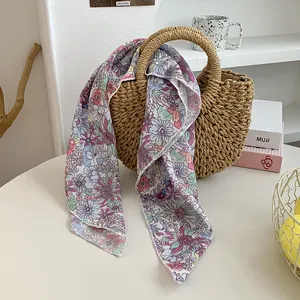 Florales Seidentuch aus Satin an einer Strohtasche für einen schicken Sommerlook
