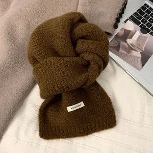 Detaillierte Nahaufnahme eines braun gestrickten Wollschals mit weicher Textur und Etikett