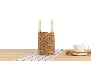 Geflochtene Papierschnur-Eimertasche mit Holzperlengriffen auf einem Dekotisch