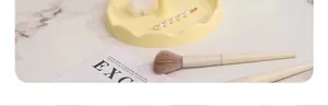 Detail view of the yellow sunflower-shaped makeup mirror base on a marble desktop with props