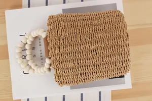 Nahaufnahme einer handgewebten Strohtasche mit runden weißen Holzperlengriffen.
