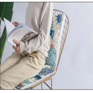 Model sitting on a chair showing a decorative ocean themed cushion cover in a room
