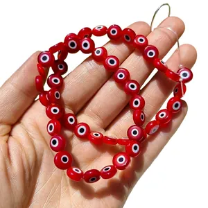 Gros plan de perles en verre œil grec rouges et plates pour la création de bijoux DIY