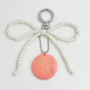 Gedetailleerd overzicht van parel strik sleutelhanger met gegraveerde roze MAMA hanger