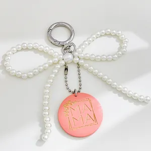 Detailopname van een parelboog sleutelhanger met een roze MAMA ronde bedel hanger.