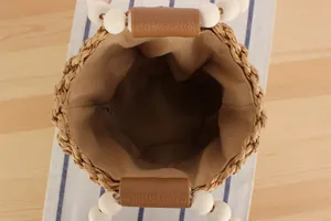 Detailansicht einer gewebten Strohtasche mit Holzperlengriff und Innenfutter aus Stoff