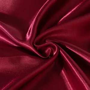 Close-up of a luxurious burgundy red satin pillowcase with soft silky sheen and elegant folds