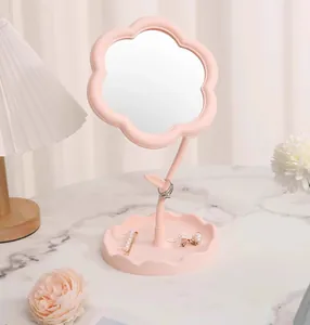 Close-up view of a pink flower shaped makeup mirror on a marble tabletop with props