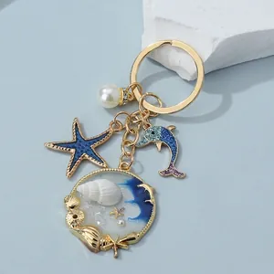 Detailed view of a marine-themed keychain with blue starfish and dolphin pendants