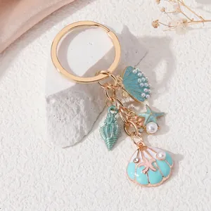 Close-up of ocean-themed gold keychain with turquoise seashell and starfish charms