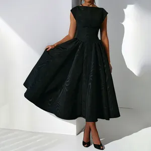 Détail d'une robe midi de luxe française noire avec un tissu texturé et jupe évasée.