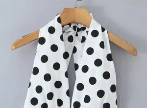 Detailansicht eines weißen Neckholder-Tops mit auffälligem schwarzem Polka-Dot-Muster.