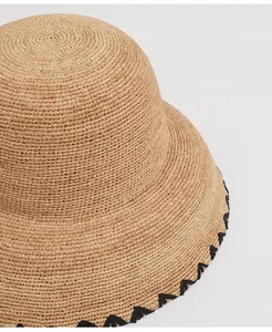 Close-up view of a high-quality woven raffia straw hat with a black embroidered edge