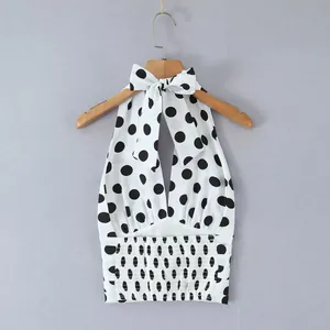 Detailansicht eines weißen Polka-Dot-Haltertops mit Smok-Taille und Schleife