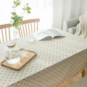 Elegant detail of a pastoral cream tablecloth with blue daisy prints and tassel fringe