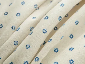 Close-up of blue daisy print on rustic beige linen tablecloth fabric texture