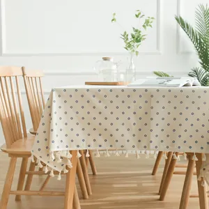 Close-up of blue daisy floral tablecloth with decorative tassel edges in home setting