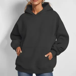 Close-up detail of women's oversized black hoodie featuring kangaroo pocket and hood.