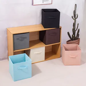 Set van kleurrijke opvouwbare stoffen opbergkubussen netjes gerangschikt in een houten plank.
