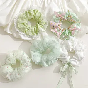 Detailansicht verschiedener grüner Scrunchies mit Spitze und Blumenmustern