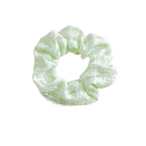 Süßes minzgrün-weiß kariertes Spitzen-Scrunchie-Haargummi auf weißem Hintergrund