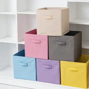 Cajas de almacenamiento plegables de tela no tejida de colores en un estante blanco.
