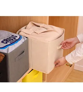 Detail of a beige foldable non-woven fabric storage box being pulled from a closet shelf