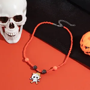 Detailopname van Halloween-halsketting met oranje kralen en cartoon skelet hanger