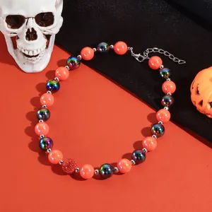 Detailopname van Halloween-kralenketting met oranje en iriserende kralen op rood.