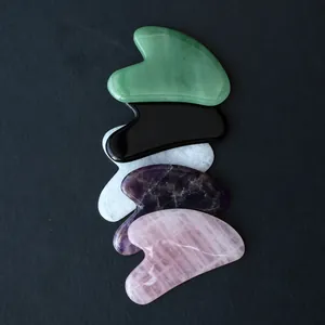 Multi-colored natural stone Gua Sha tools including rose quartz and amethyst for facial massage