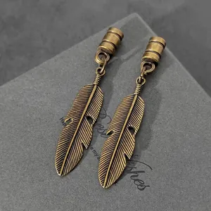 Primer plano de colgantes de plumas de bronce vintage con texturas grabadas detalladas