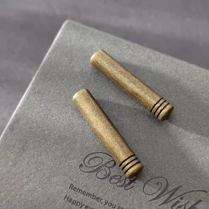 Primer plano de los extremos de cordón cilíndricos de bronce antiguo con patrón grabado