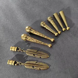 Primer plano de dijes de plumas de bronce y terminales de cordón grabados