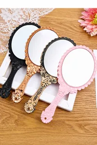 Detailed view of vintage handheld makeup mirrors with ornate embossed handles in four colors