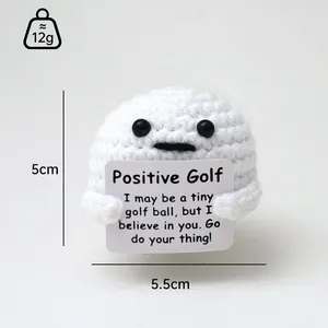 Vista detallada de un mini muñeco de pelota de golf a ganchillo con mensaje positivo.