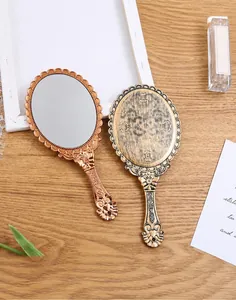 Detail showing the elegant vintage floral engraving on the back of a handheld mirror