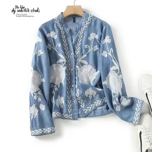 Detailed view of heavy white floral embroidery on a premium blue V-neck Tencel shirt