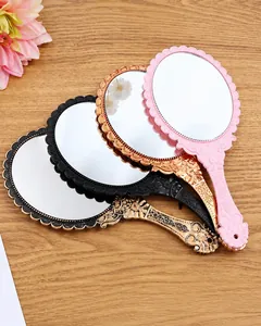 Macro view of vintage handheld mirrors with ornate European floral lace patterns on wood