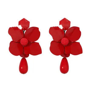 Detailed macro view of vibrant red flower earrings featuring a glossy teardrop pendant