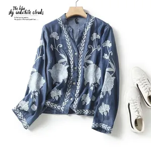Detailed macro view of white floral embroidery on a blue V-neck tencel shirt for women