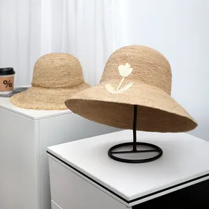 Close-up of a handmade raffia straw hat with white embroidered flower detail