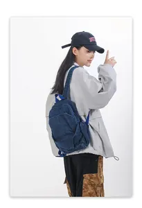 Vista trasera de la mochila de mezclilla lavada en una modelo para detalles de estilo.