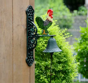 Detail view of a vintage cast iron rooster doorbell mounted on a wooden post in a garden