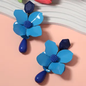 Close-up view of vibrant blue metal flower earrings featuring deep blue teardrop pendants