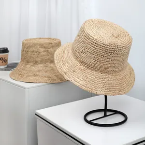 Close-up of fine raffia straw bucket sun hat with large brim on display stand
