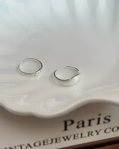 Detailed macro view of S925 sterling silver wavy rings on white ceramic plate background