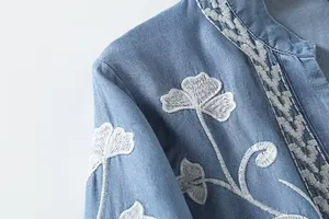 Macro detail of white floral embroidery on a premium blue Tencel long sleeve shirt