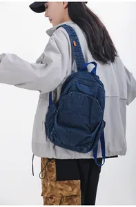 Vista lateral detallada de una pequeña mochila de mezclilla azul en una modelo.